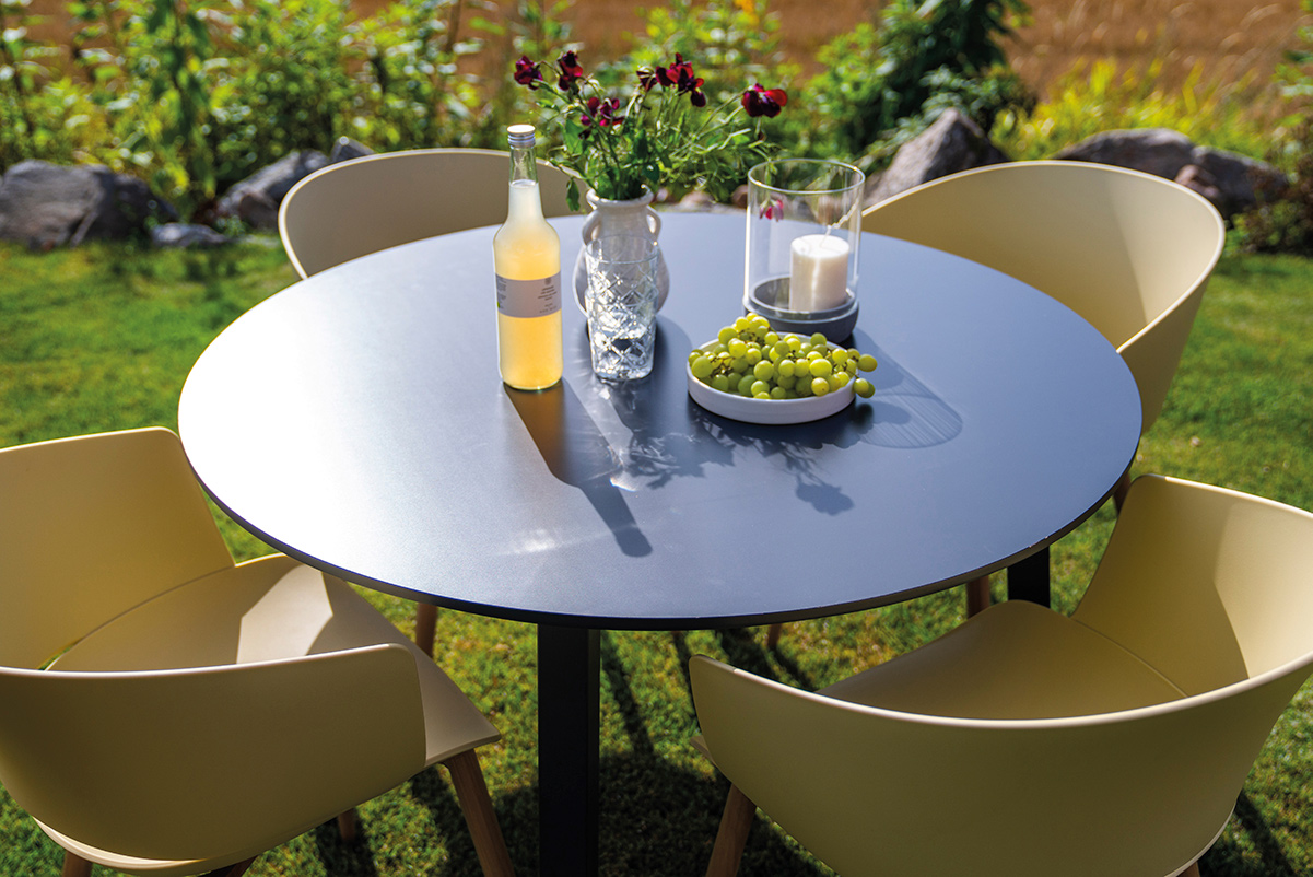 Sort rundt utebord med fire stilrene plaststoler