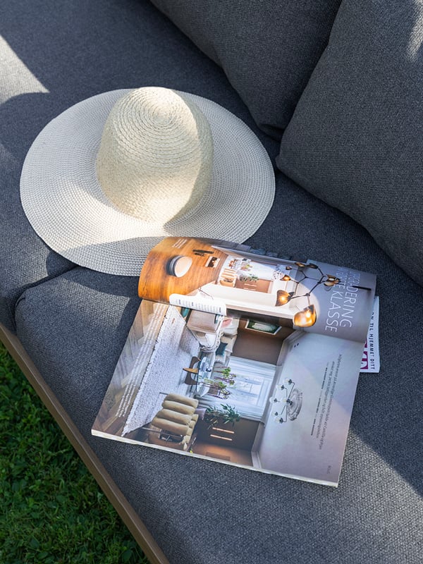 Nærbilde av utesofa på plen foran hvit hus