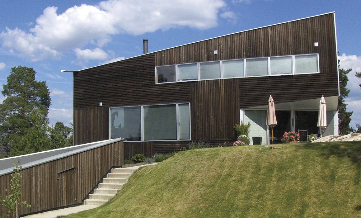 Moderne hus med stående og liggende, mørk trekledning og store vindusflater.