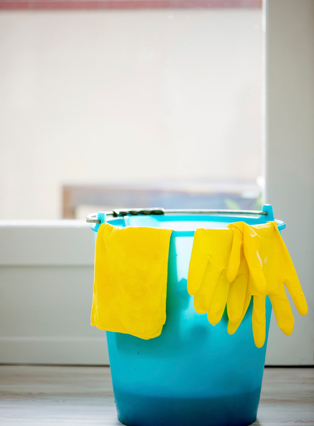 Gule gummihansker og nal liggende over blå bøtte på kjøkken