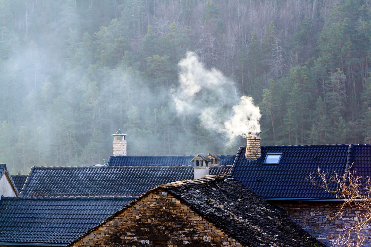 Enebolig med vedfyring hvor røyk stiger opp fra pipen på taket.
