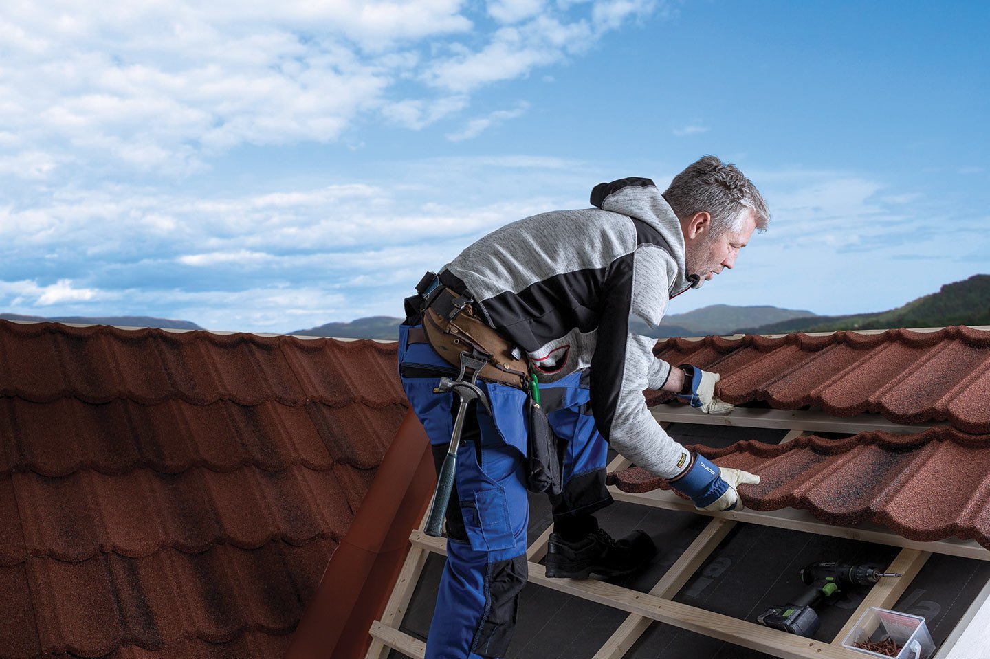 Håndverker monterer takstein på et tak