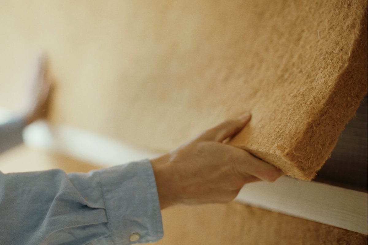 Nærbilde av trefiberisolasjon som presses inn i vegg – naturlig isolasjonsmateriale