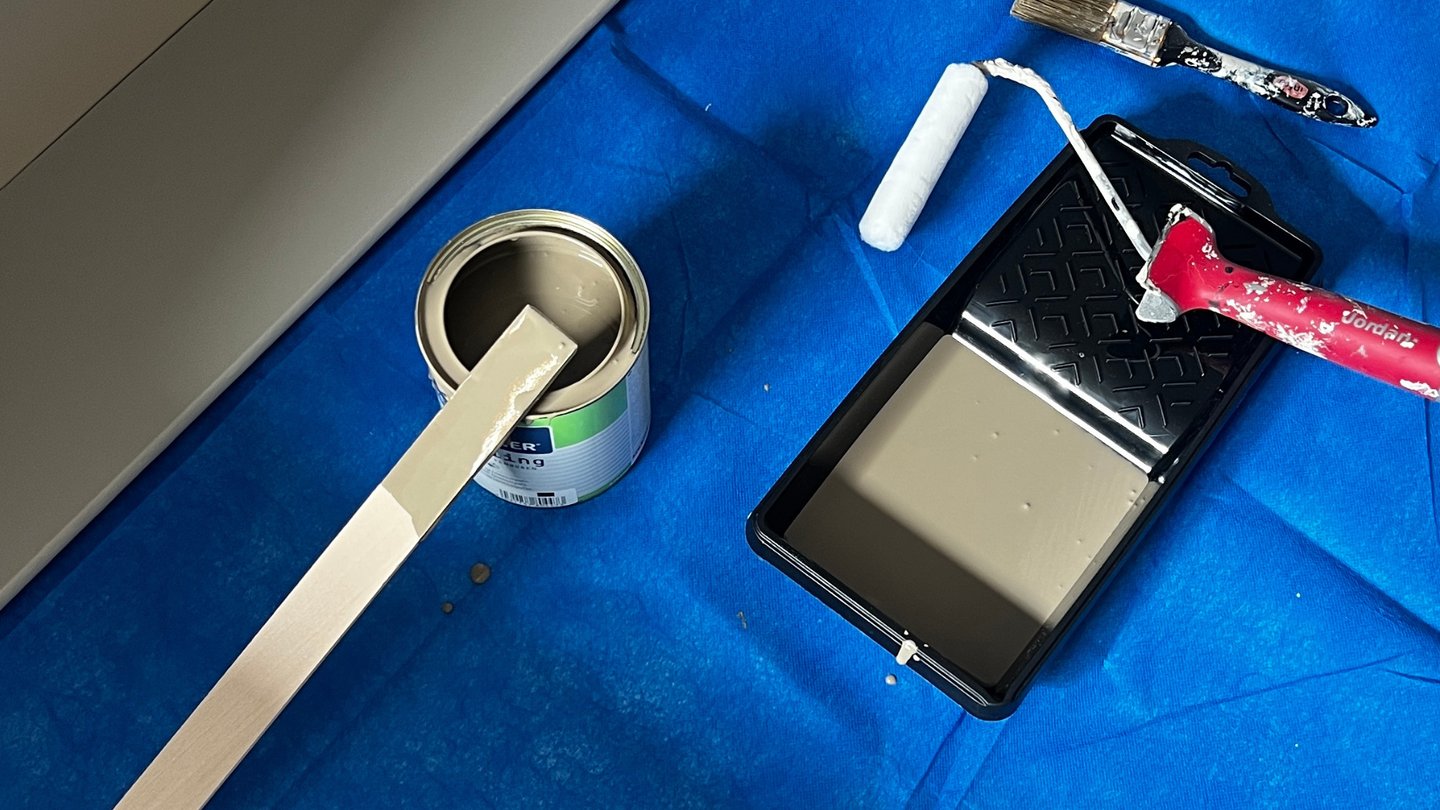 Malingsutstyr og maling på blå presenning.