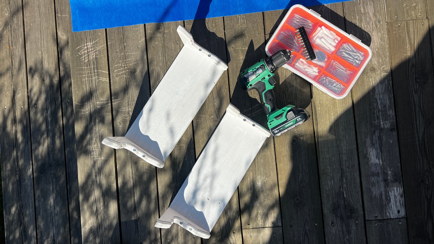 Ferdig grunnete hylledeler med drill og skruer ved siden av.