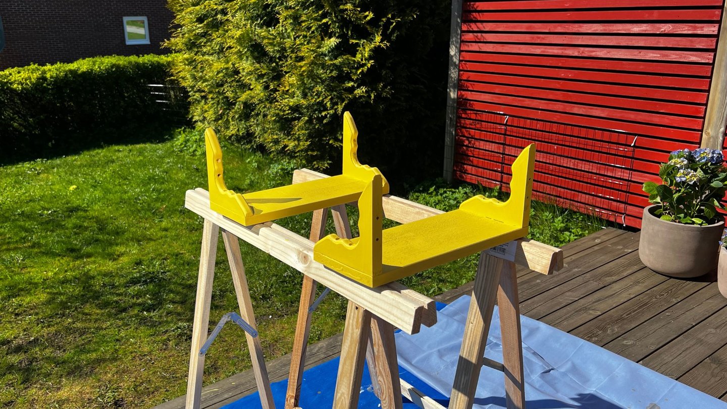 Hyller malt i gult, står til tørk ute.