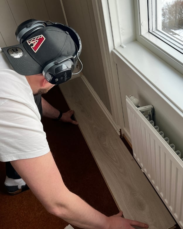 Mann legger først planke laminatgulv i et rom