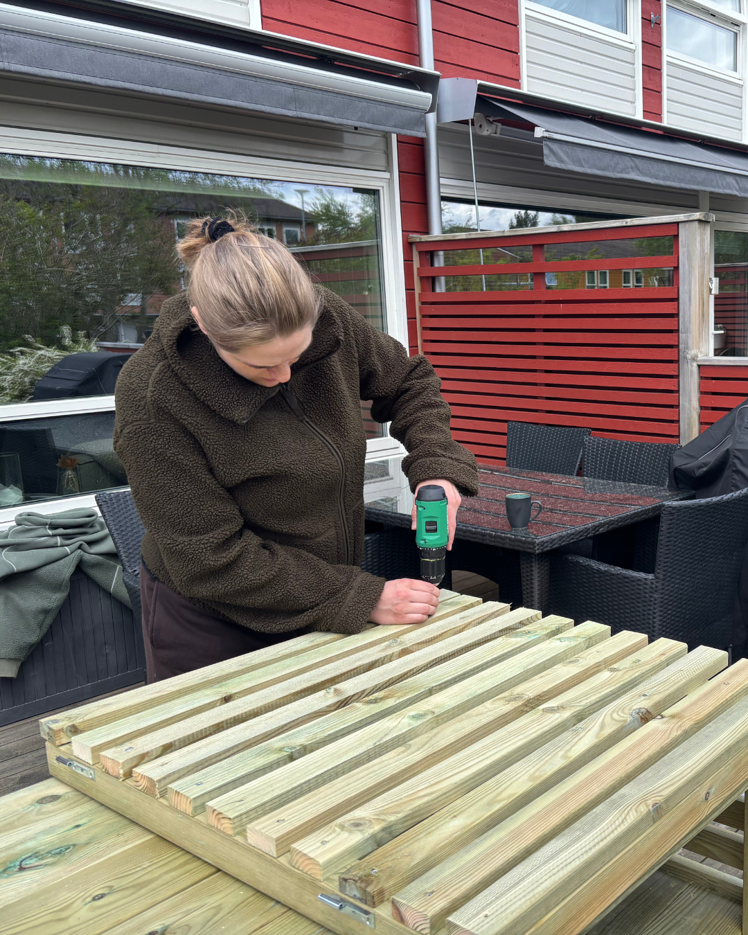 Kvinner driller skruer inn i dør av spiler til utekjøkken