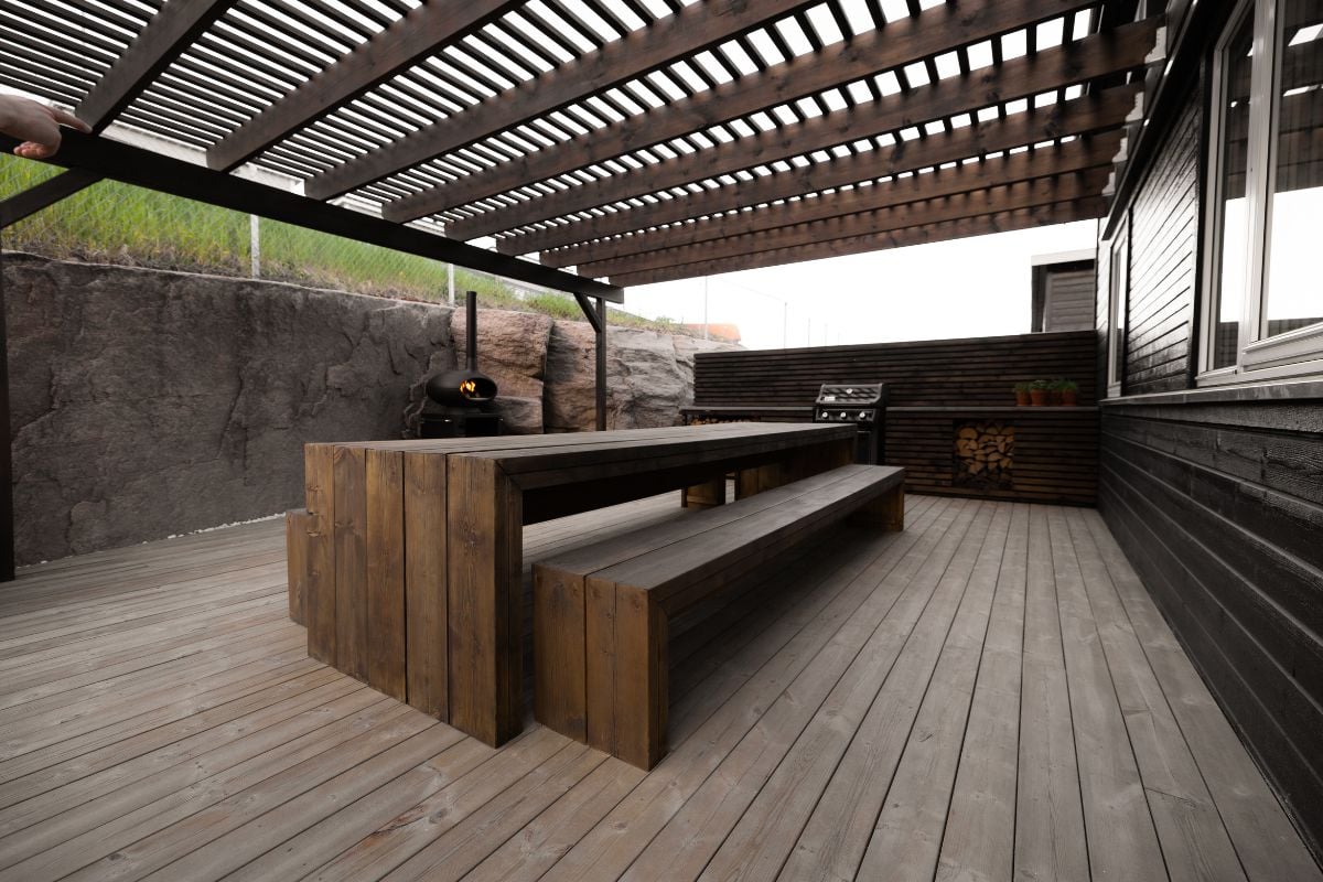 Terrasse med sittegruppe og overbygg, beiset i mørk farge.