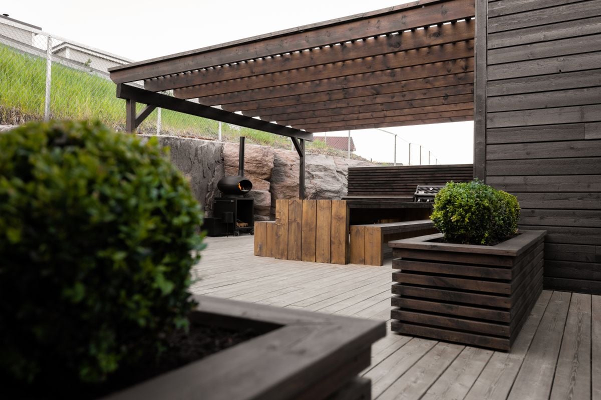 Detaljbilde av beiset terrasse med blomsterkasse på tredekke.