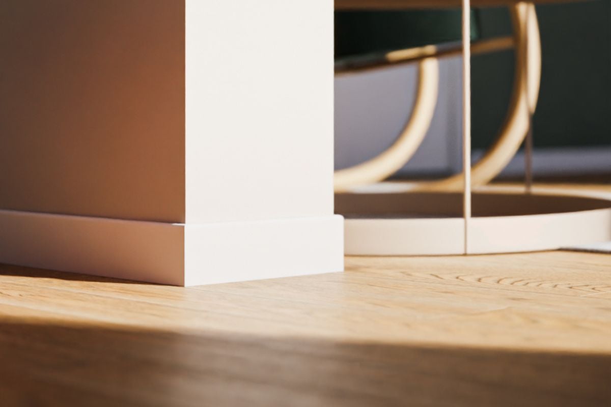 Nærbilde av hvit gulvlist med sprekkbeskyttelse og lys parkett