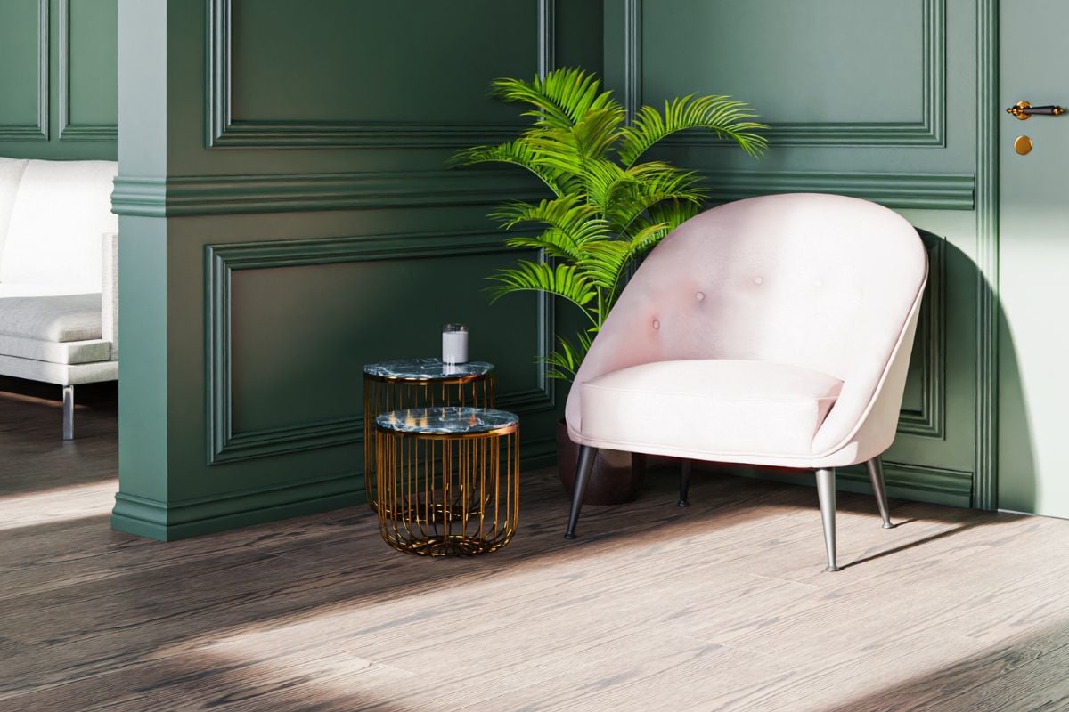 Stilren grønn vegg med hvite lister, rosa stol og grønn plante i potte