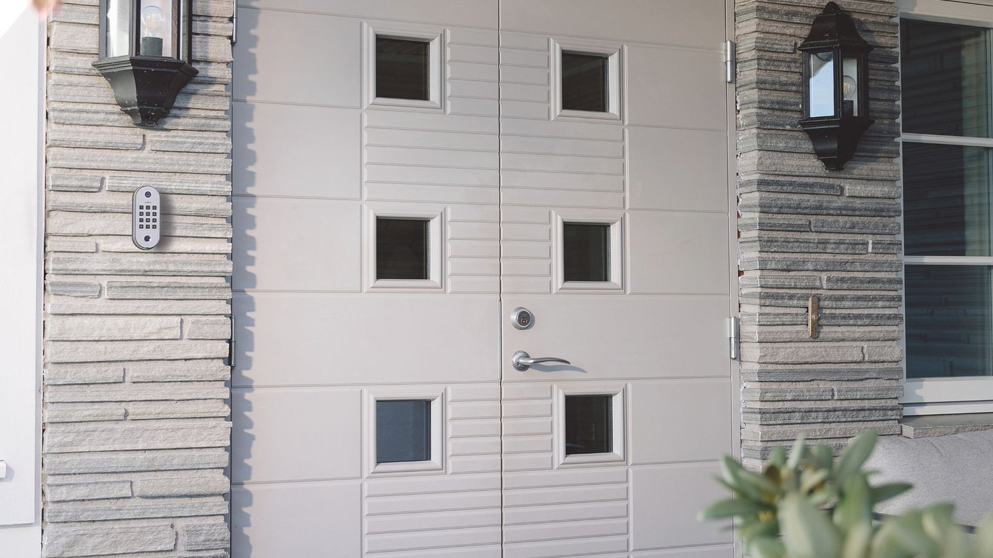 Moderne inngangsparti med hvit dobbel ytterdør og kodelås montert ved siden av døren.