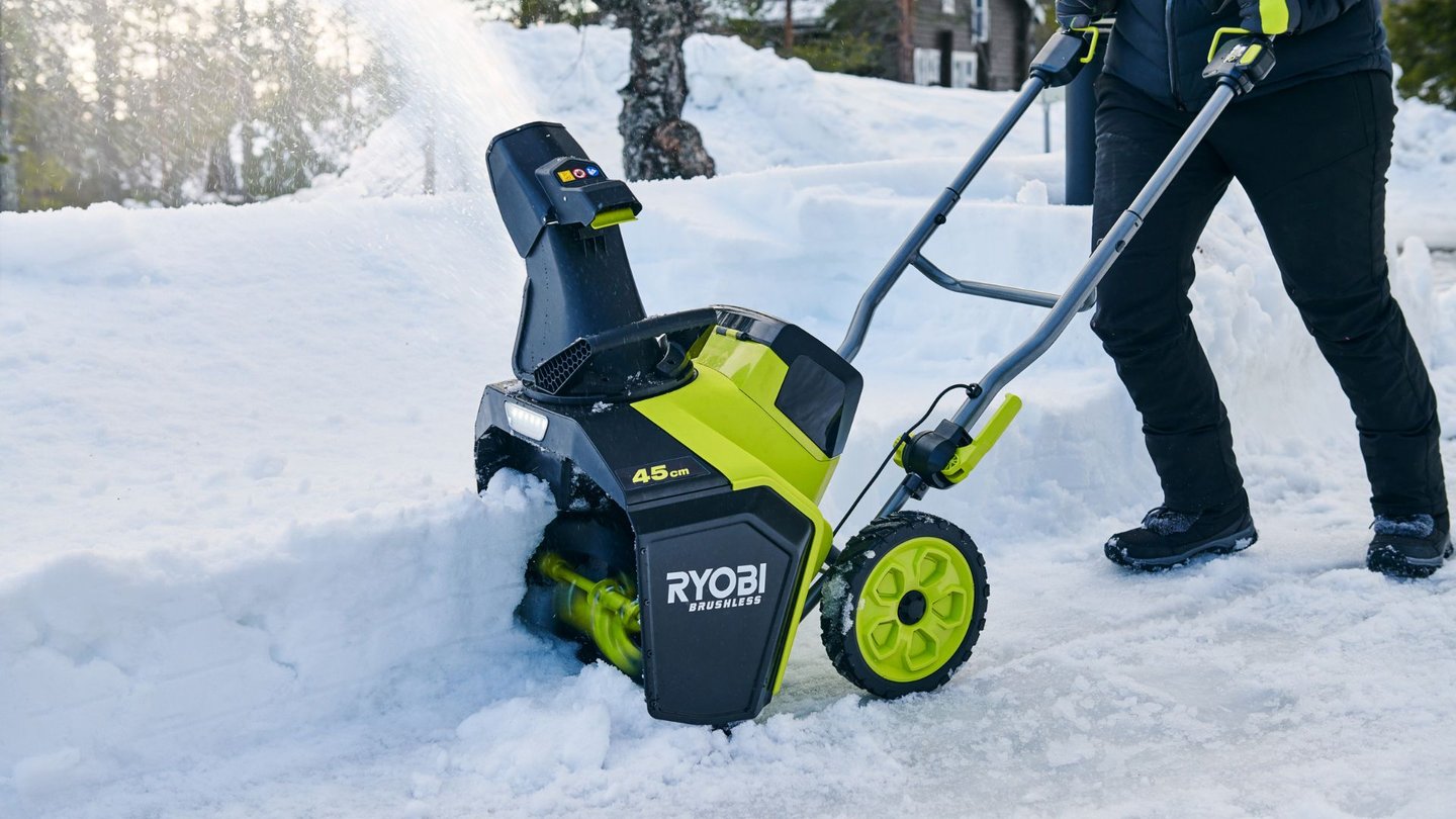 En person bruker en Ryobi snøfreser til å rydde snø i oppkjørsel.