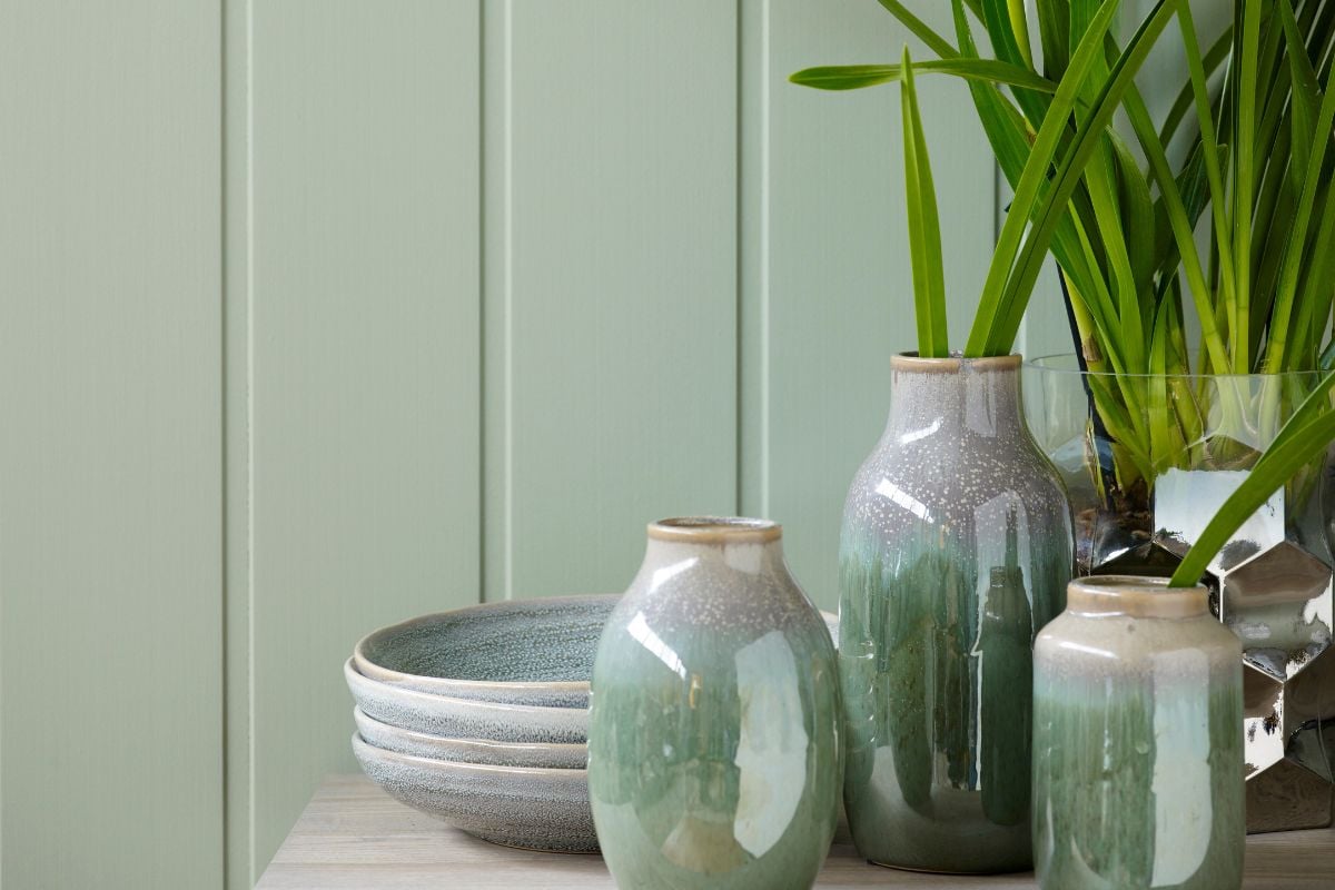 Grønn vegg med vaser og planter foran