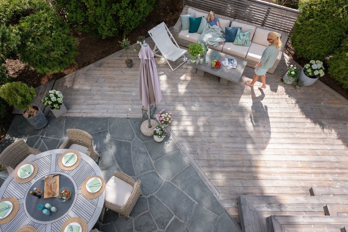 Uterom av belegningsheller og treverk, et rundt pådekket bord med blomster