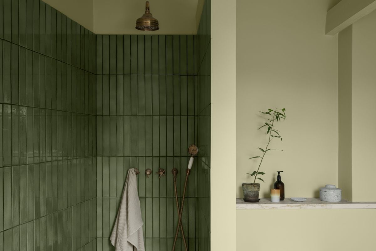 Baderomsvegg med grønne fliser og tilstøtende slett, mattmalt vegg i dusjsone.