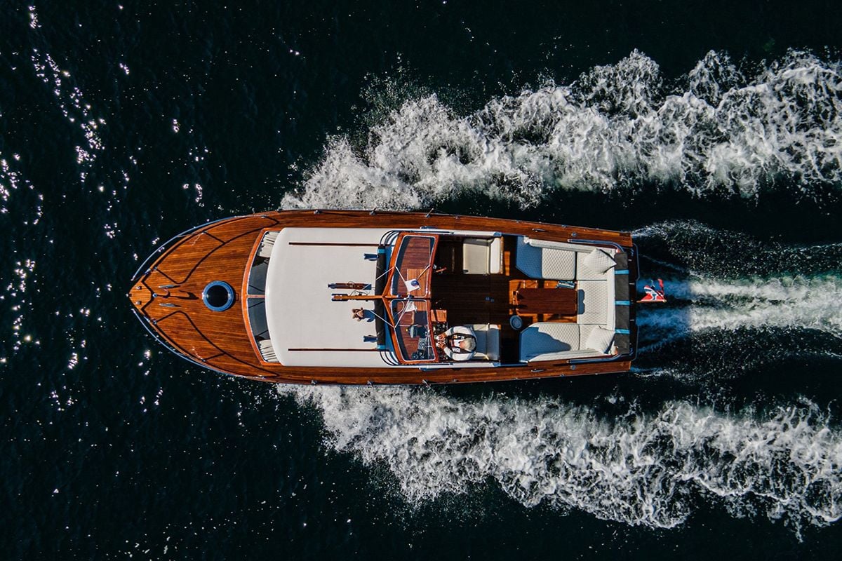 Dronebilde av motorbåt i fart sett ovenfra, med tydelige kjølvannsstriper.