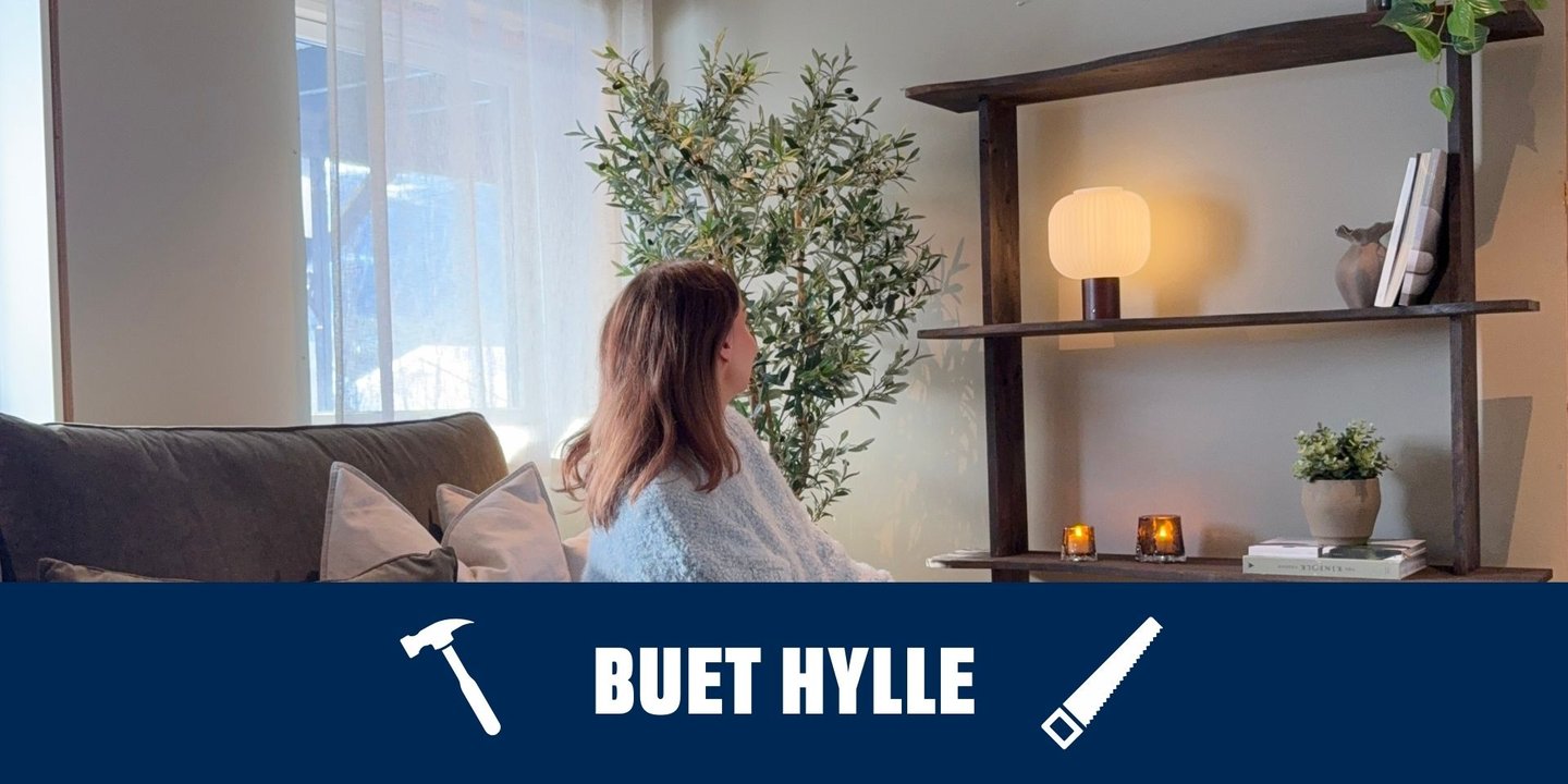 Dame som sitter i sofa i stuen og ser på en buet hylle med dekorasjoner.