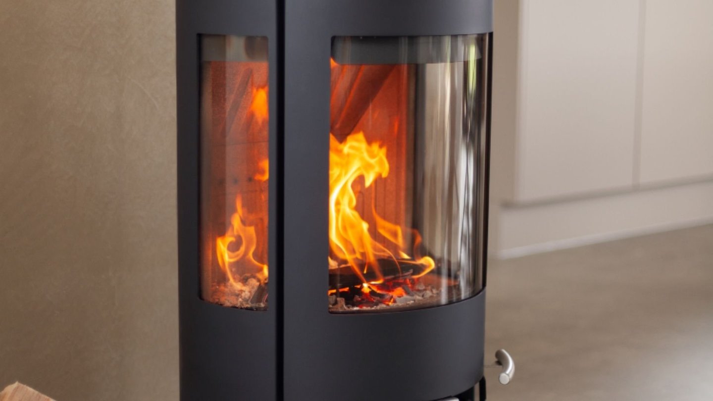 En svart Aduro 17 peisovn med flammer stående på en glassplate.