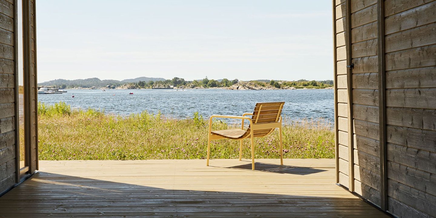 En stol i tre på en terrasse en solfylt dag ved havet.