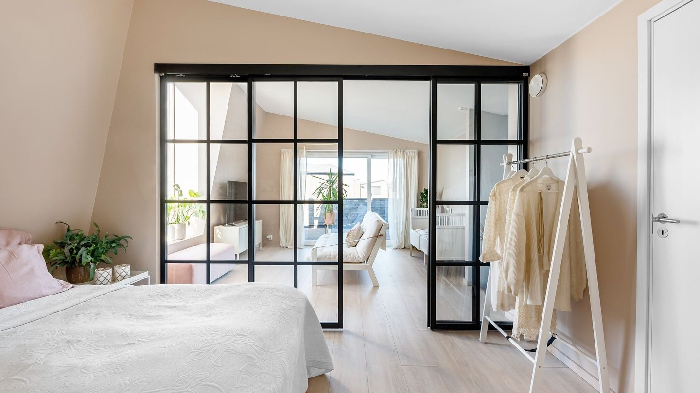 Soverom med svarte glasskyvedører og moderne interiør.