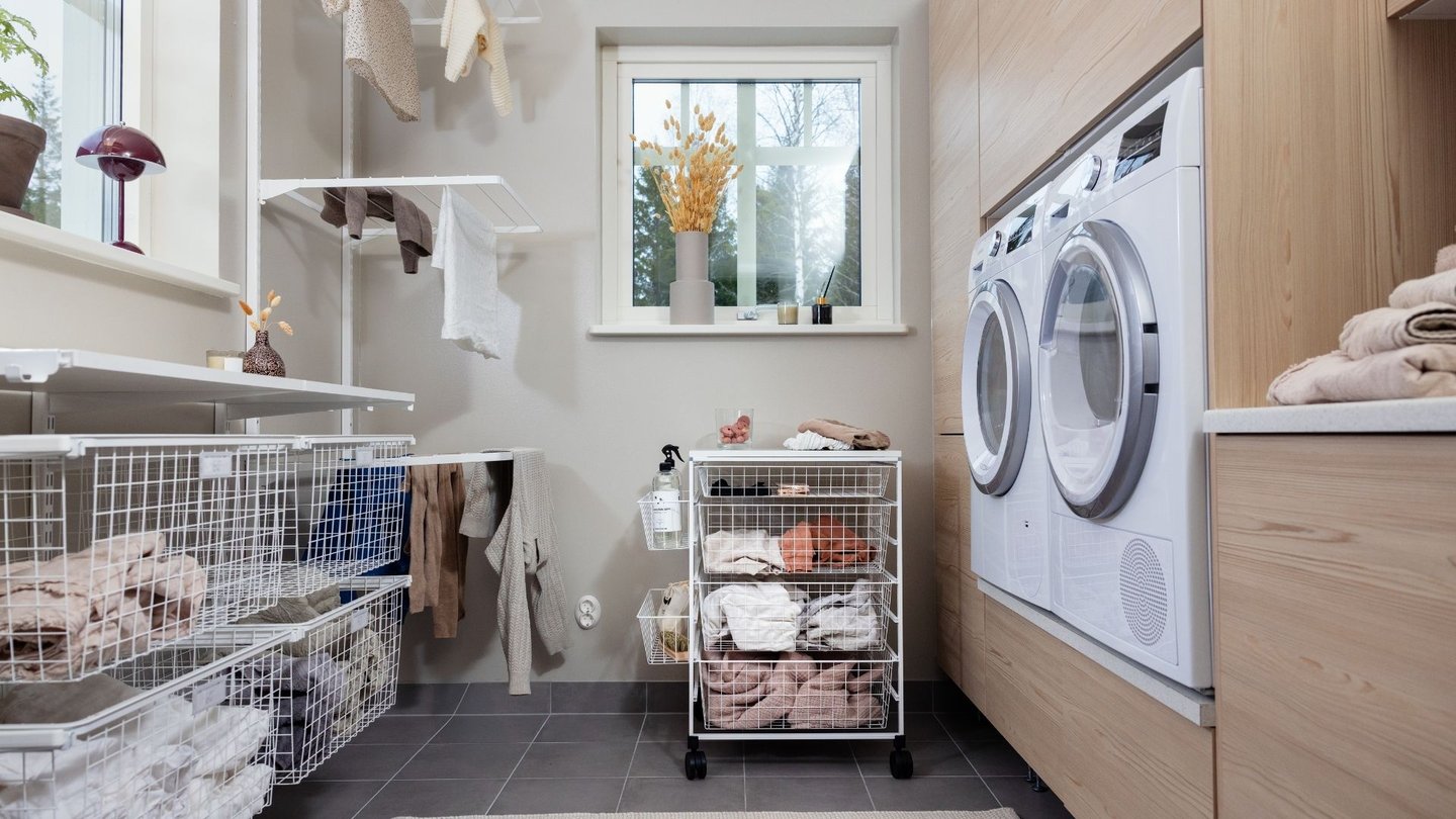Bildet viser et lyst og organisert vaskerom. Til høyre i rommet står en vaskemaskin og en tørketrommel side om side.