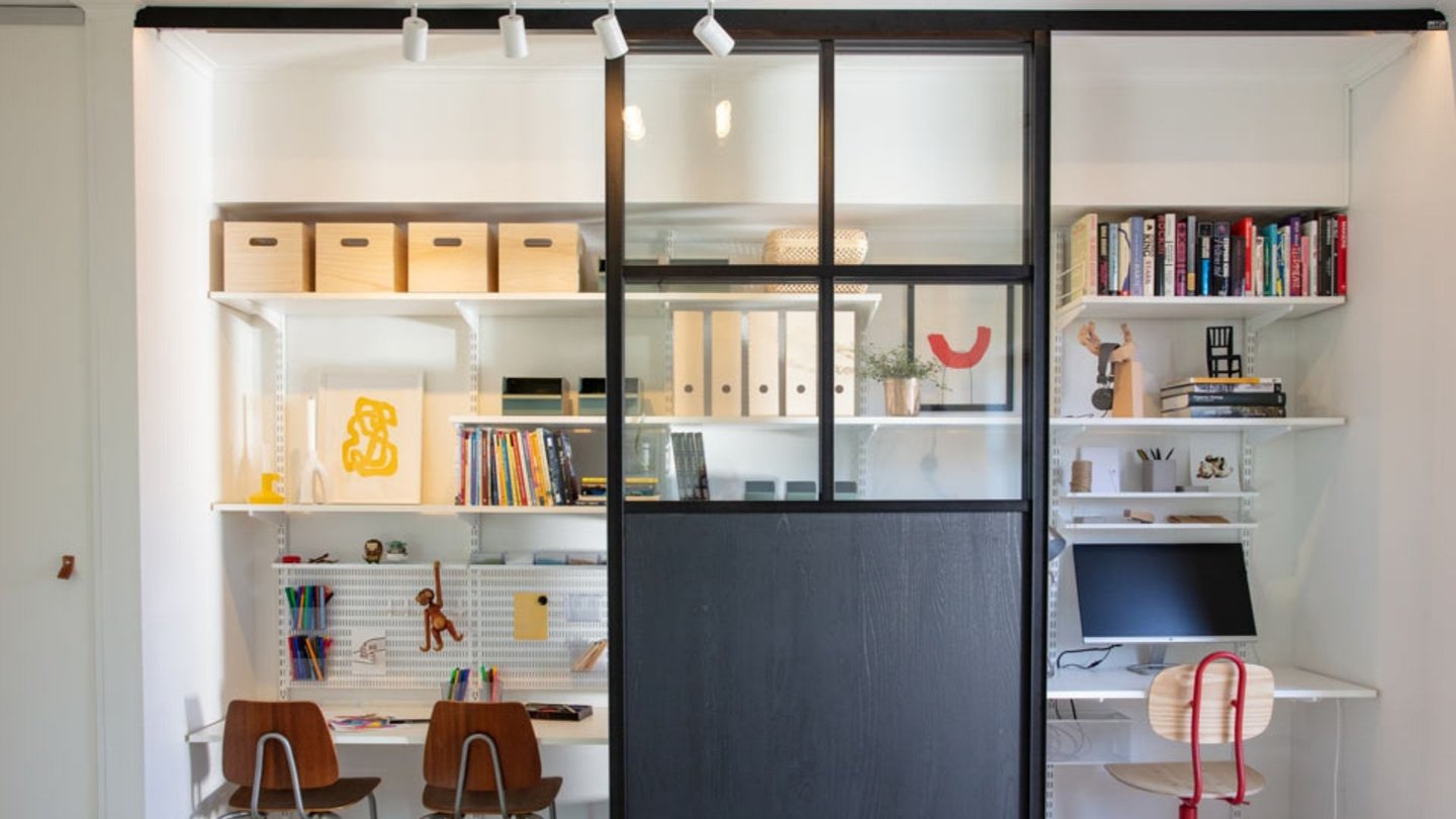 Bildet viser et moderne hjemmekontor bak en svart glasskyvedør i industristil