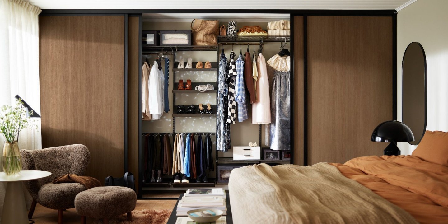 Soverom med skyvedørsgarderobe i mørk eik, åpen løsning med organisert oppbevaring av klær og sko.