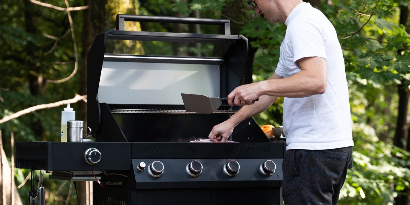 Mann i hvit t-skjorte som står ut og griller på grill fra FCC