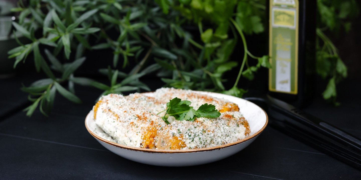 Grillet mais i en skål med en dressing over seg.