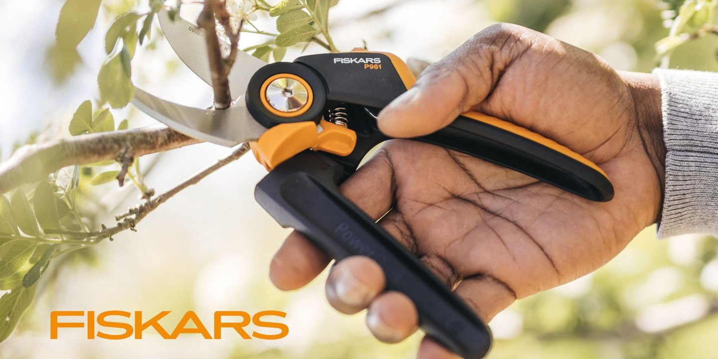 Svart og oransje hagesaks fra Fiskars som klipper grener i solen