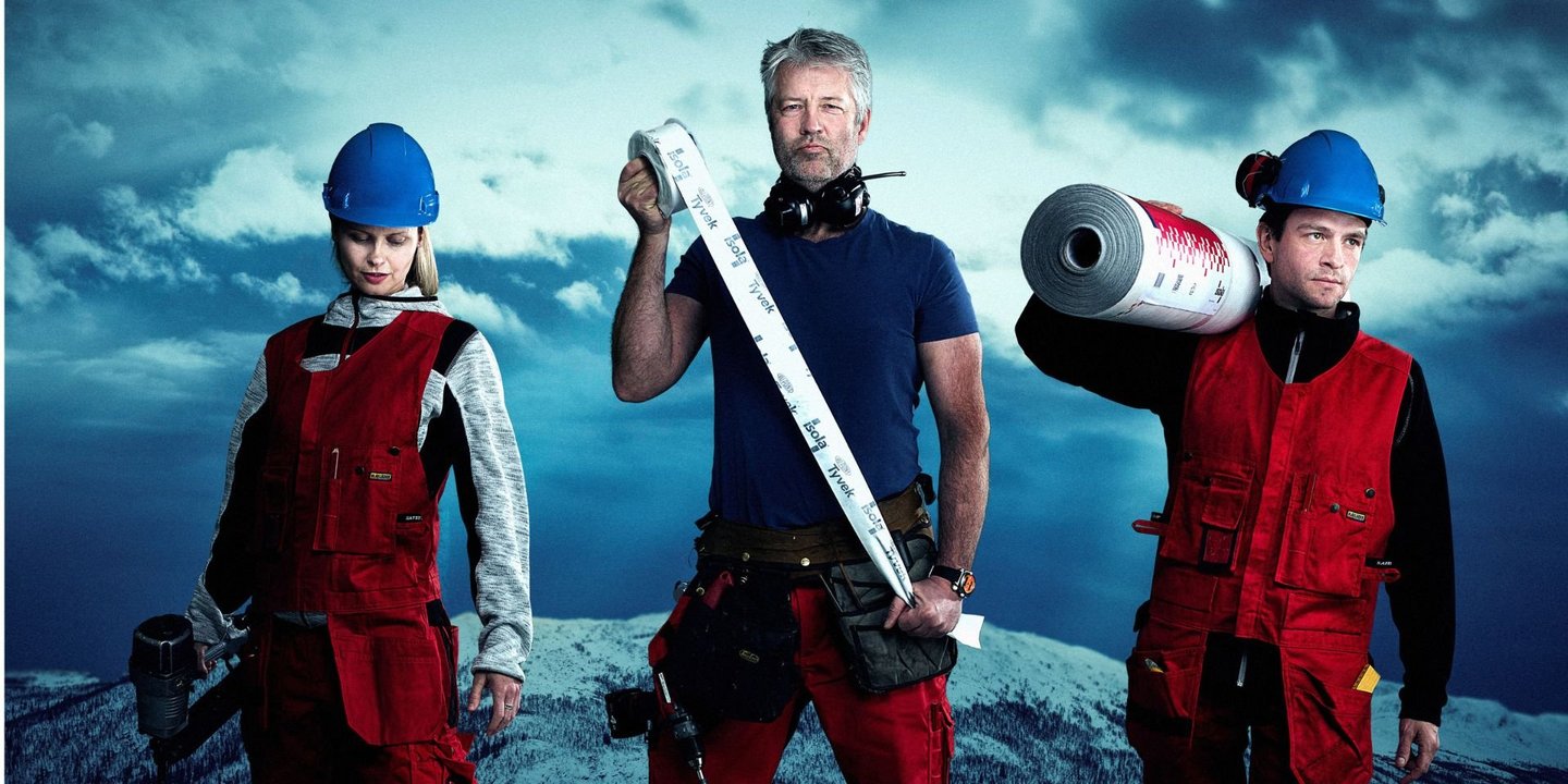 En kvinne til venstre som holder en spikerpistol og to menn til høyre som holder ulike produkter. Det er dårlig vær i bakgrunnen. 