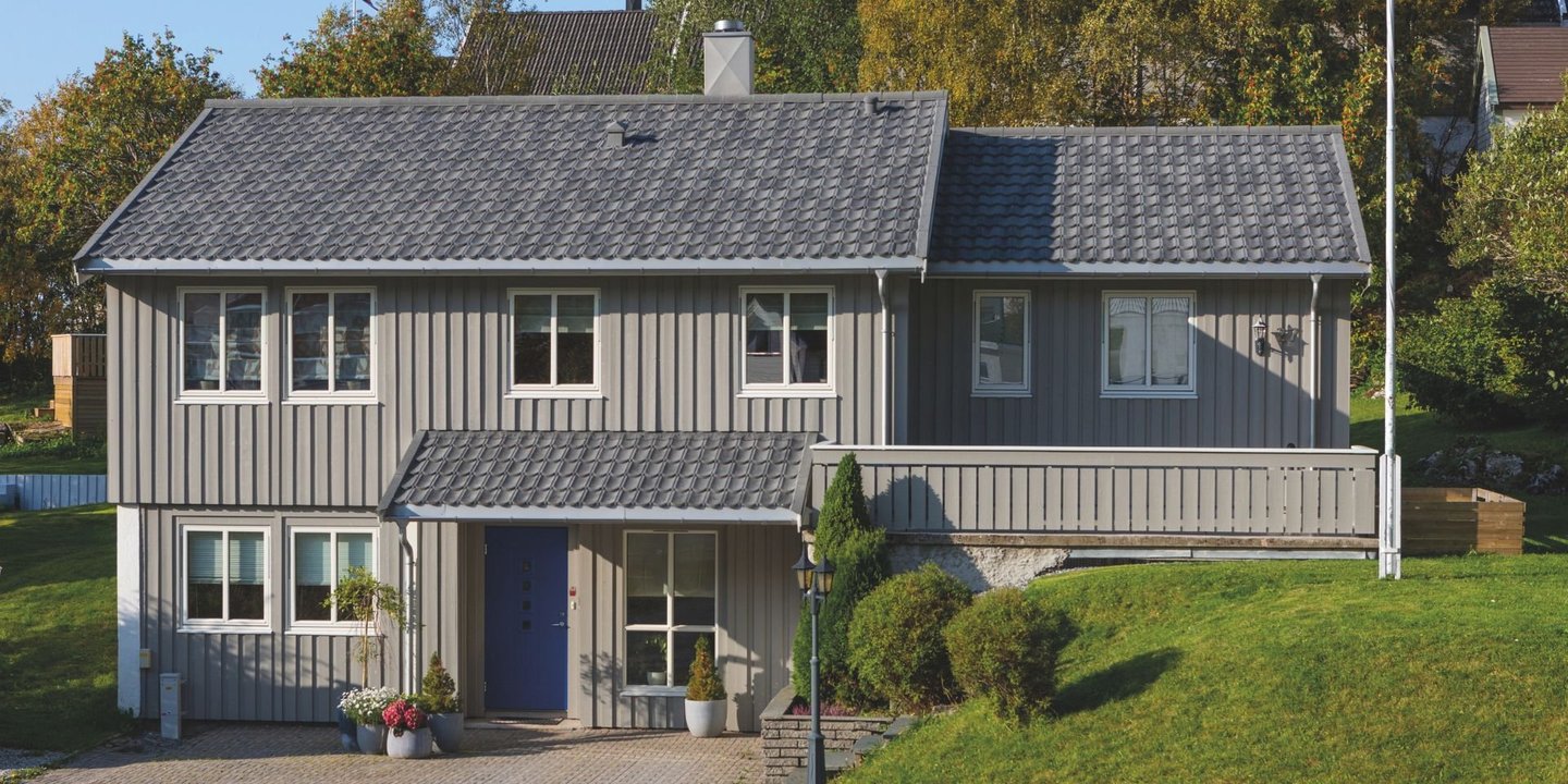 Grått hus med grått tak fra Isola. Huset har en grønn plen foran seg.