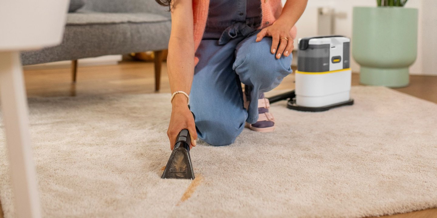 Kvinne rengjør teppe i stuen med tekstilrenser fra Kärcher