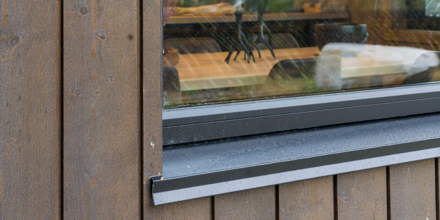 Nærbilde av brun panel. Man ser også litt av hjørnet på et vindu.