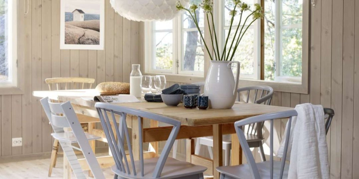 Et spisebord med ulike stoler rundt. Rommet er i medium lys panel og i taket henger det en hvit lampe. Det er godt med dagslys som fyller rommet.