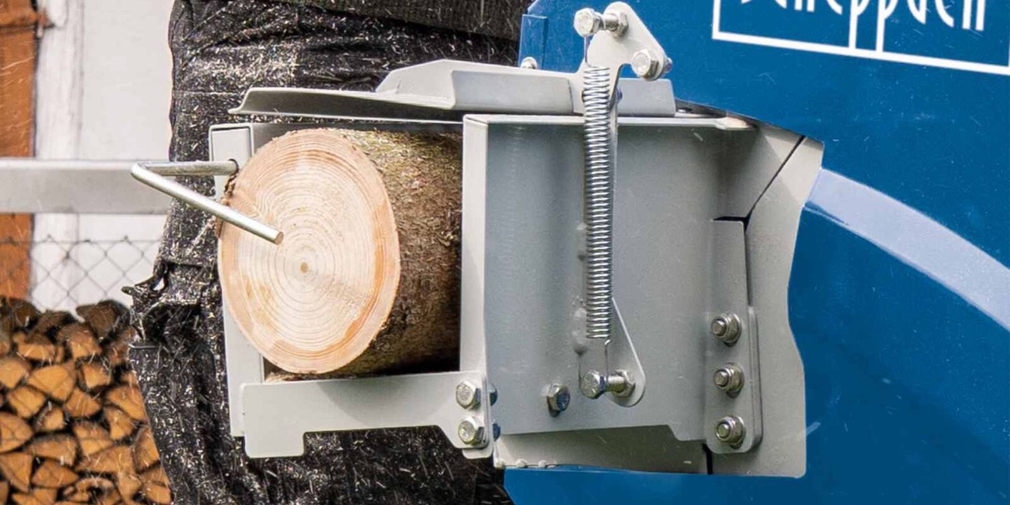 Vedkubbe i klemme på Scheppach vedkløyver før kapping, utendørs foran vedstabel.