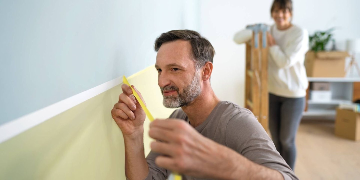 Mann som maskerer vegg med maskeringstape