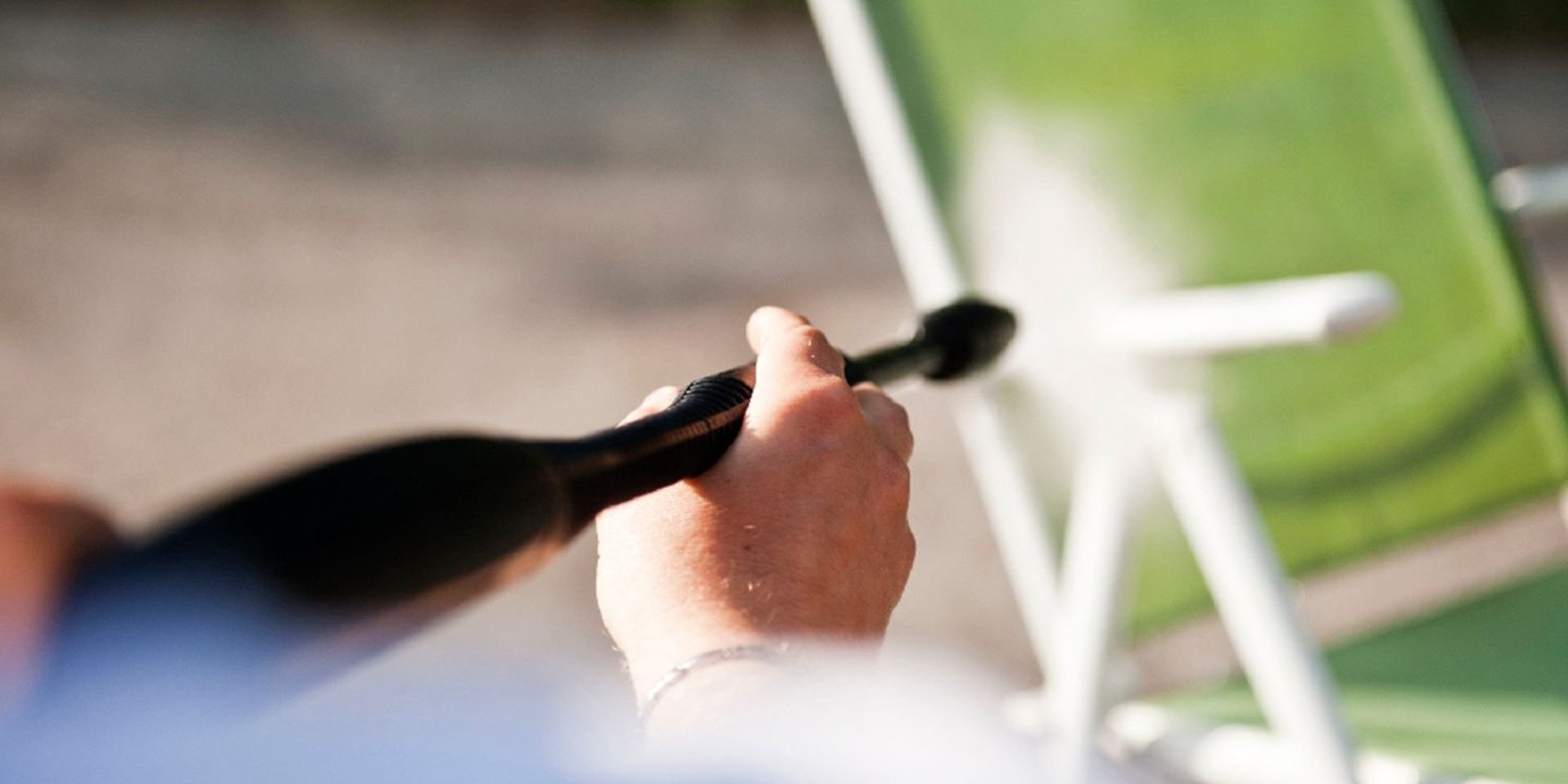 Person spyler en grønn utestol med høytrykkspyler.