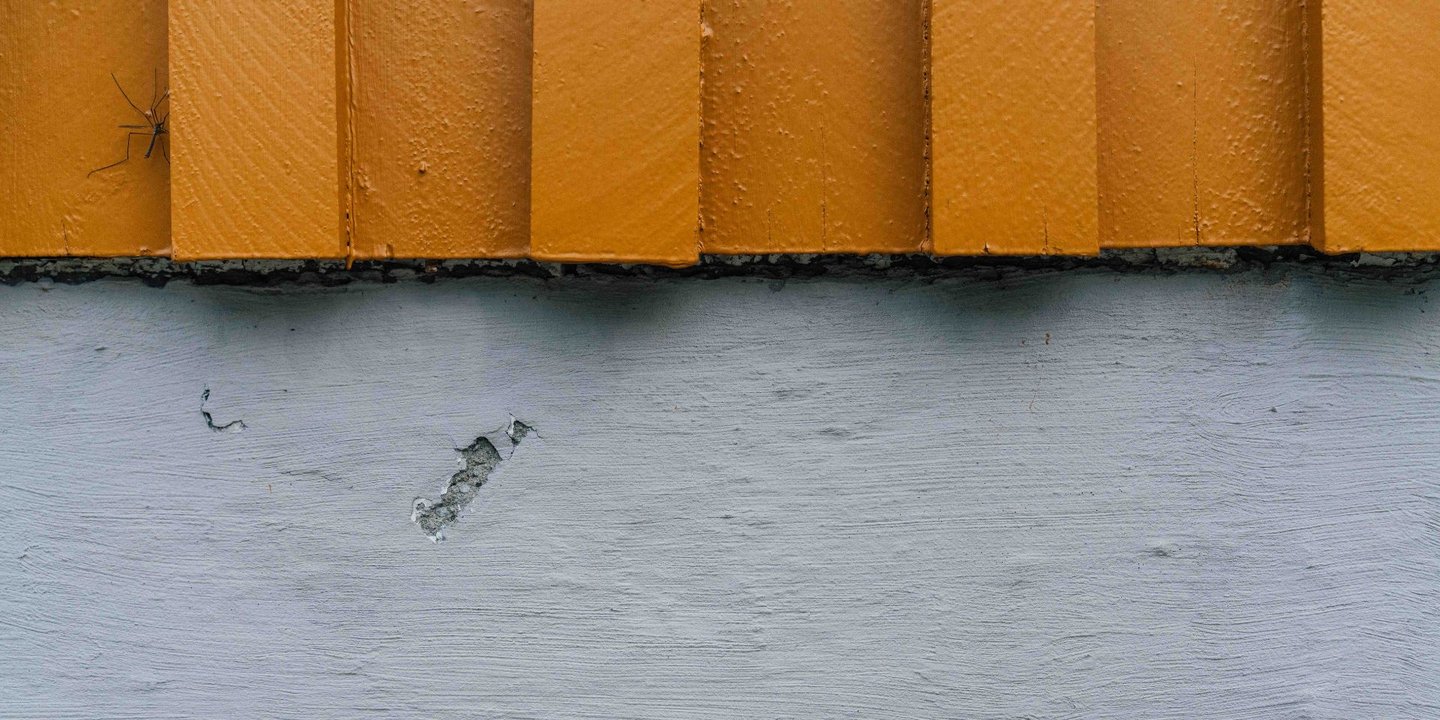 Grå grunnmur på et gult hus