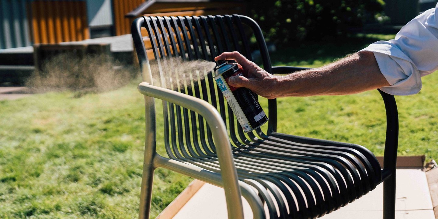 Person som spraymaler en utestol i svart