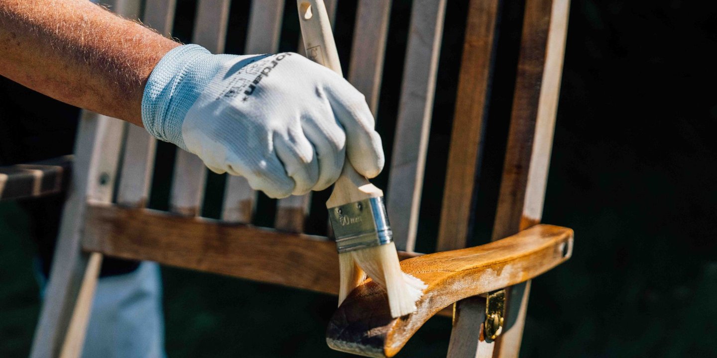 Person oljer stol av tre utendørs