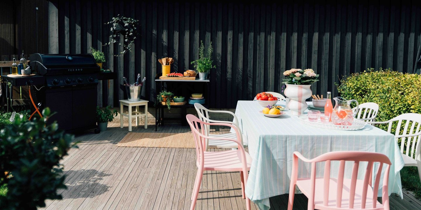 Bilde av hender som jobber med å sette opp maskeringsteip mellom husvegg og terrasse.