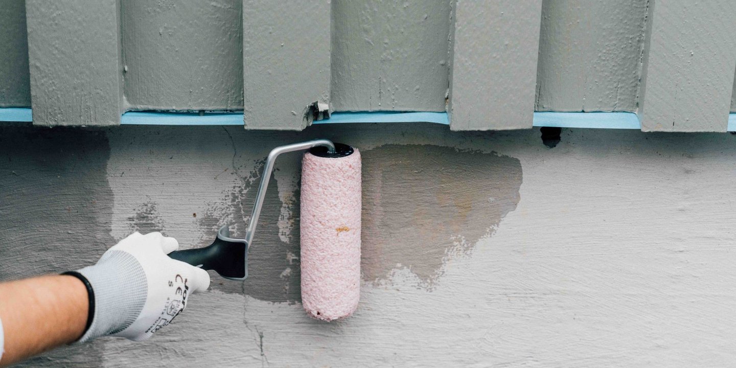 Person som maler grunnmur med rulle.