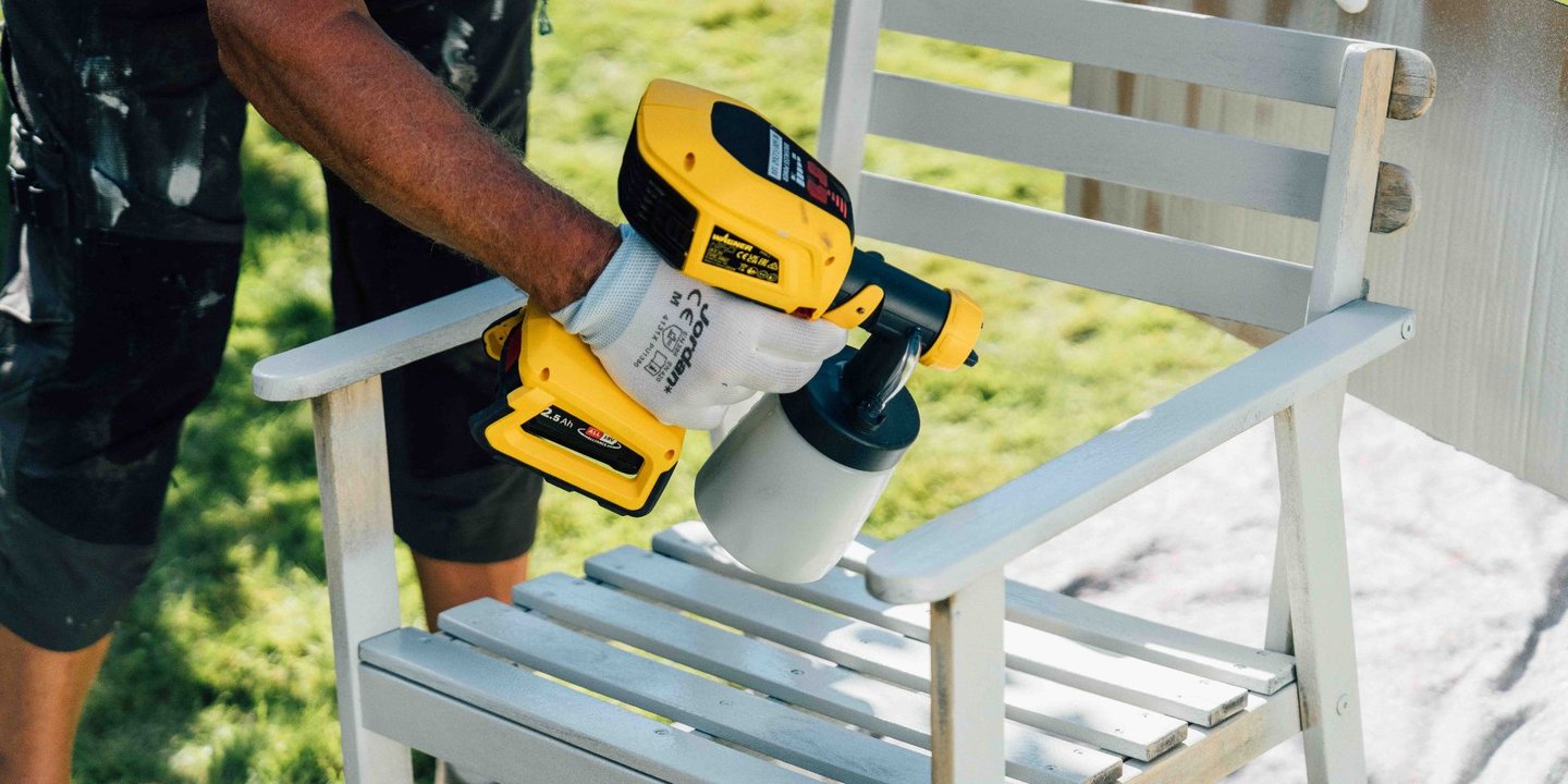 En person maler med en maskin som lett påfører malingen jevnt.