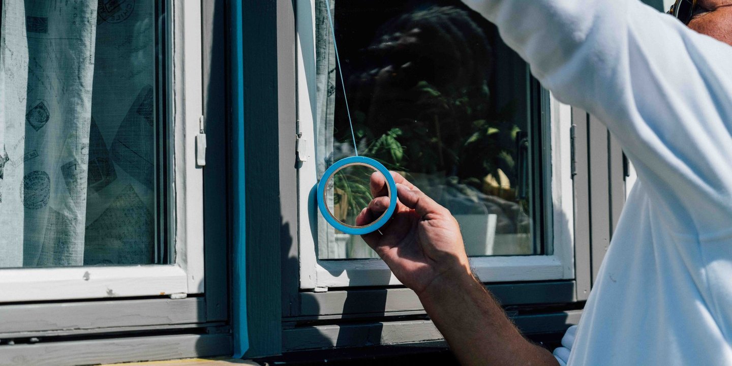 En person som maskerer opp et vindu med maskeringstape.