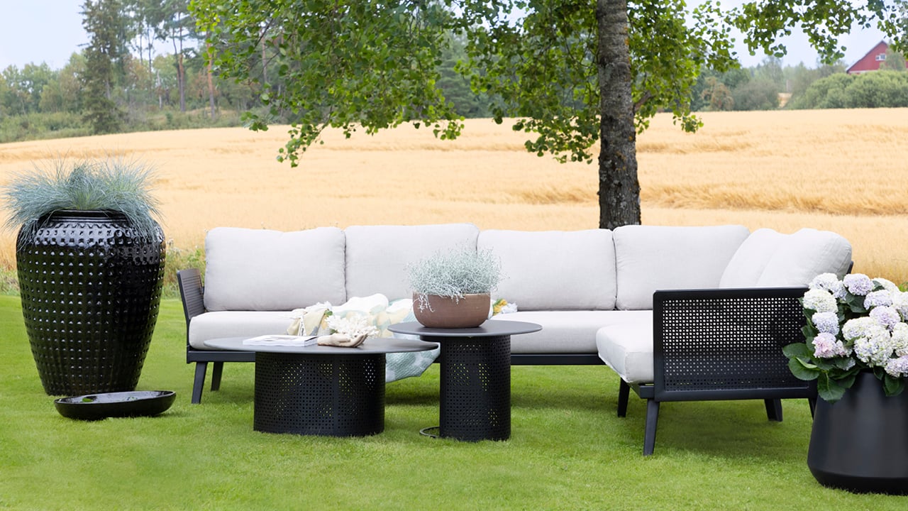 Bohem Ullern hjørnegruppe på en gressplen med en stor sort blomsterpotte ved siden av.