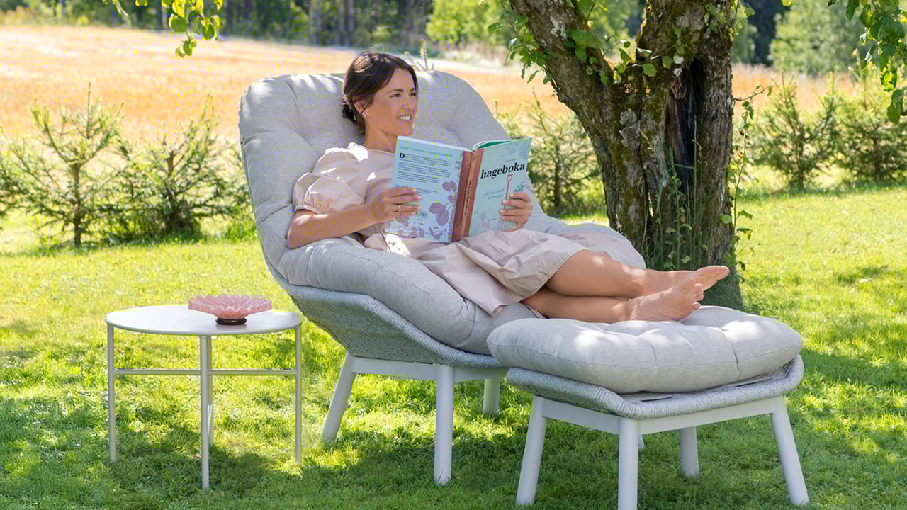 Dame i Bohem Risør stol med fotskammel under et tre. 