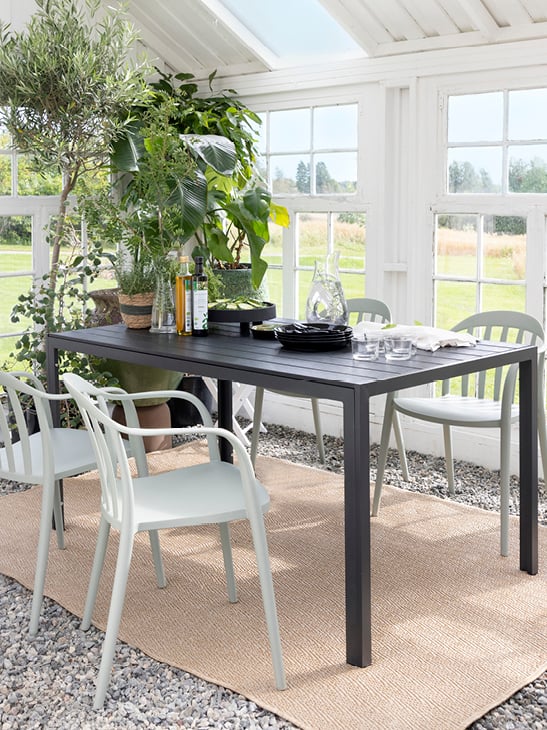 Bohem Vika stol i Moss Green rundt Bohem Nyheim bord i en vinterhage.